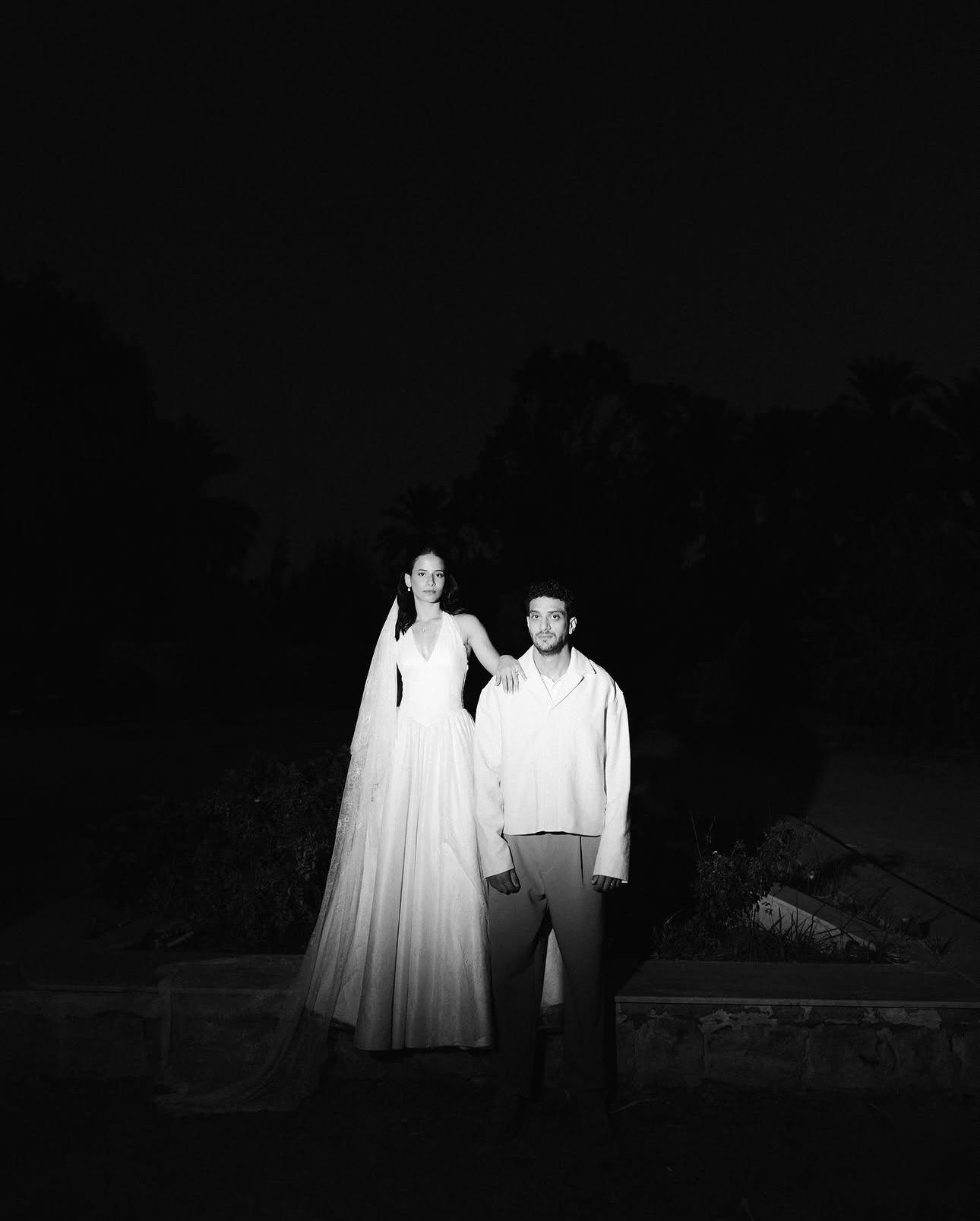 Bride and groom standing together in a dark garden at night
